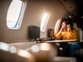 Young woman sitting on an airplane with headphones on, looking out the window before posting a pic o...