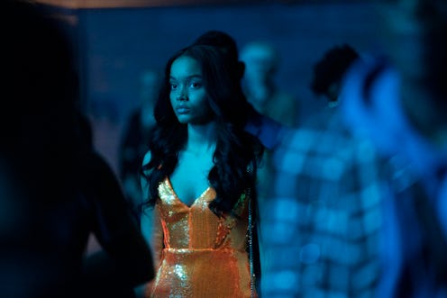 A character from Gossip Girl standing in a dark club. Her dress is orange and looks neon in the blue...