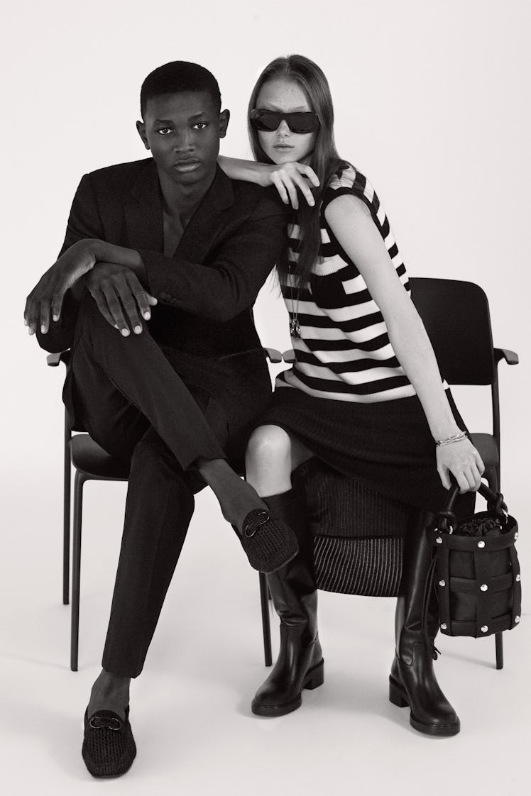 A boy and a girl posing for a photo while sitting on chairs and wearing Salvatore Ferragamo shirts, ...