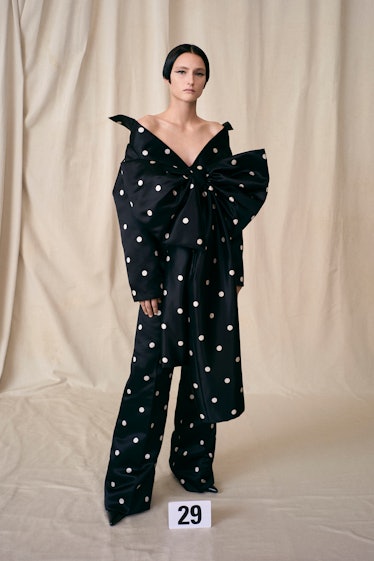 A model in a black polka-dotted Balenciaga Couture Fall 2021 jumpsuit with a bow on the waist