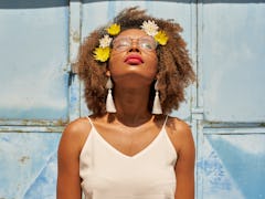 Young woman with red lips wearing glasses and flowers in her hair looking up during the July 2021 ne...