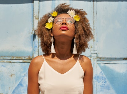 Young woman with red lips wearing glasses and flowers in her hair looking up during the July 2021 ne...