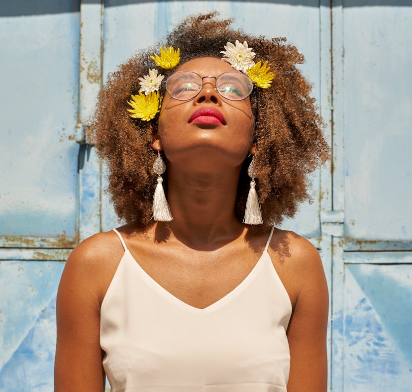 Young woman with red lips wearing glasses and flowers in her hair looking up during the July 2021 ne...