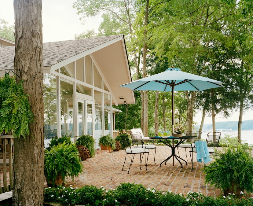 backyard patio with small round dining table and blue umbrella 