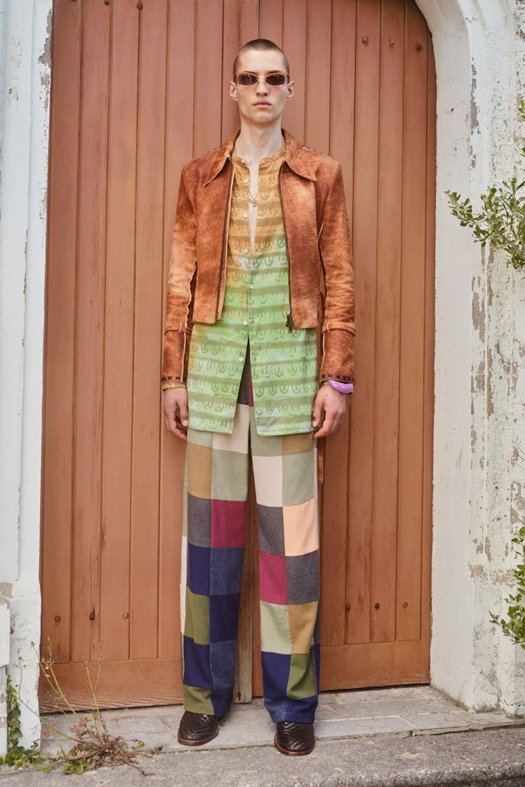 A model in a green-orange shirt, orange jacket and patchwork pants by acne at Men’s Fashion Week Spr...