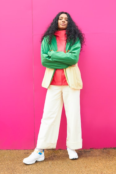 Young Cancer woman looking at the camera with a bright pink background.