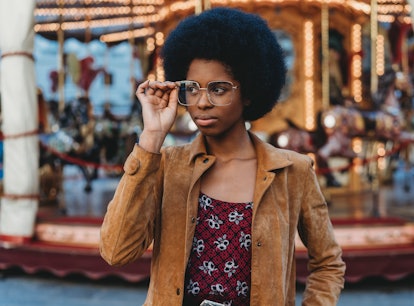 Young women peering over her glasses at an amusement park, being one of the most manipulative zodiac...