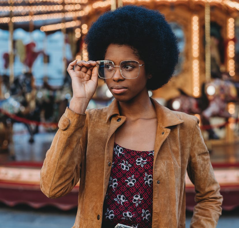 Young women peering over her glasses at an amusement park, being one of the most manipulative zodiac...