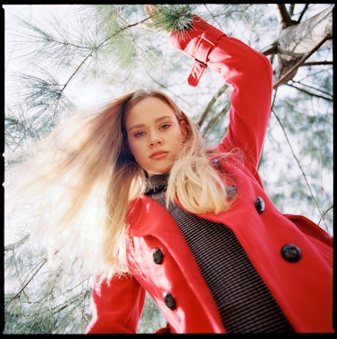 Young woman in a red coat staring down at the camera as one of the most manipulative zodiac signs.