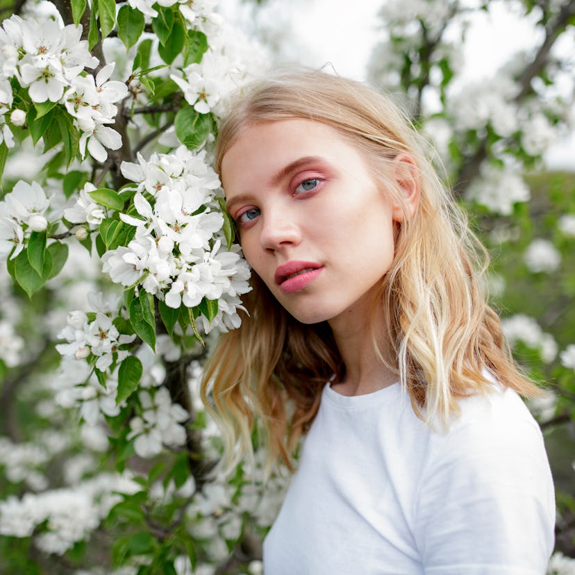 Young woman with a stellium in her birth chart, according to astrology, surrounded by white blossoms...