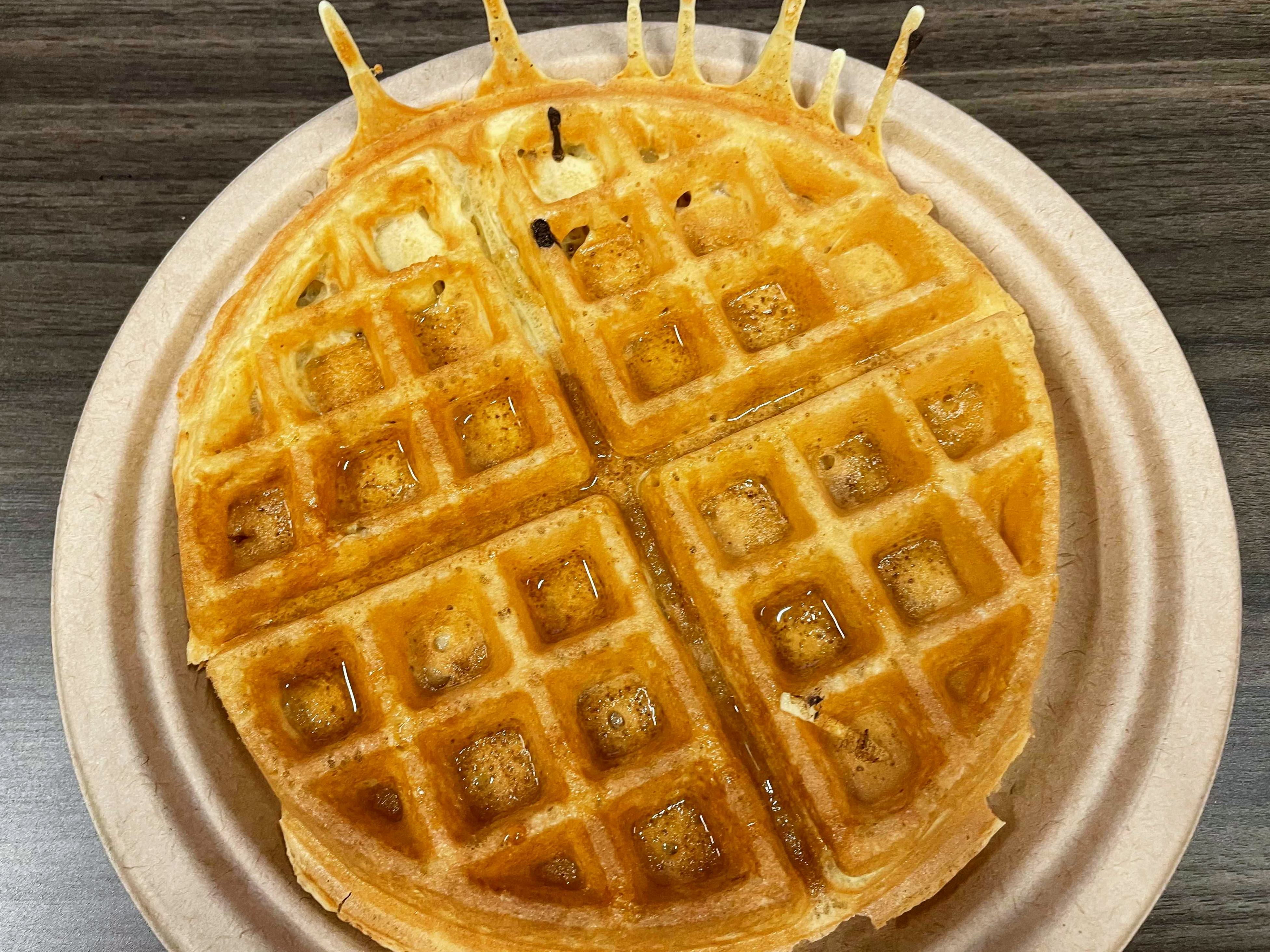 A golden brown waffle on a paper plate.