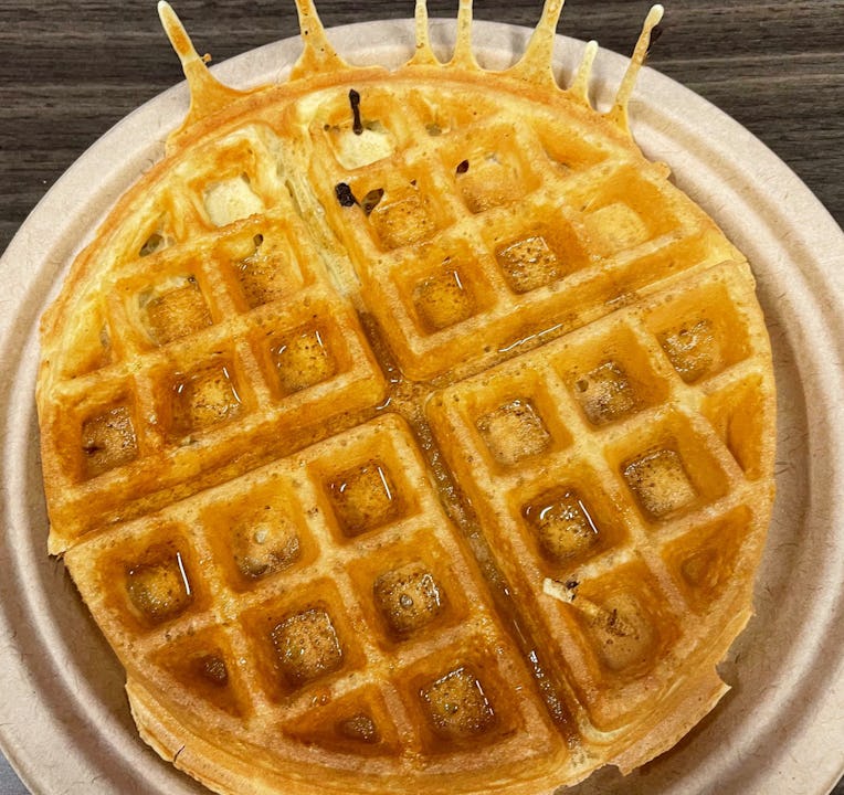A golden brown waffle on a paper plate.
