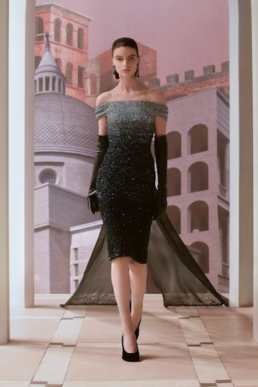 A model walking the runway in an off-the-shoulder grey and black shimmery Fendi gown with a sheer bl...