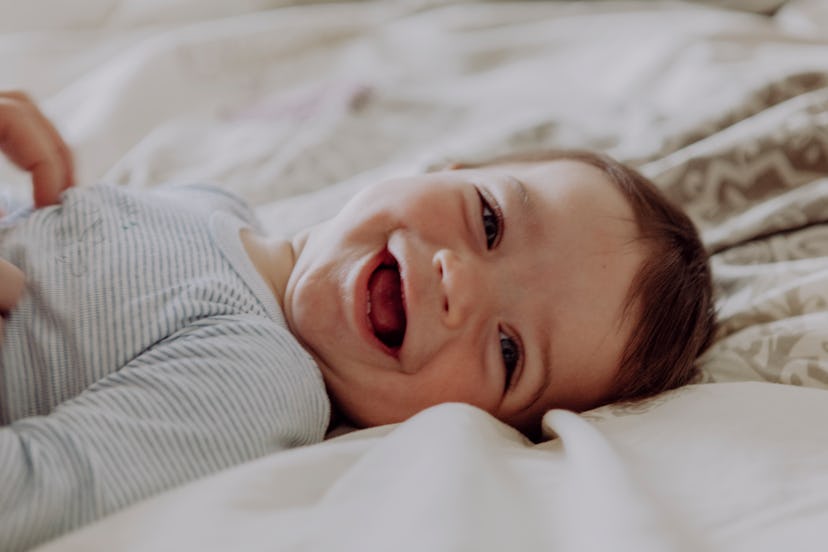 happy baby lying in bed, laughing, top j baby names