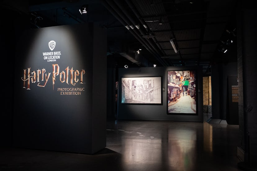 a picture of an exhibition room where photos of diagon alley are displayed against a black backdrop