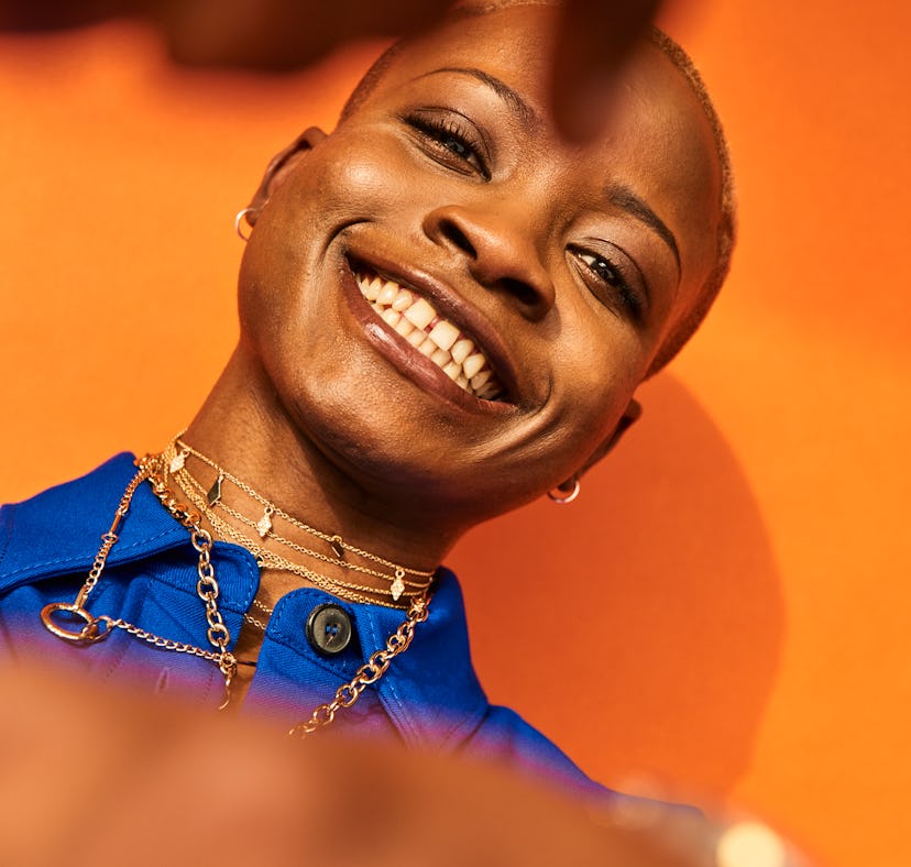 Young woman in front of an orange background, having the best week of July 12, 2021.