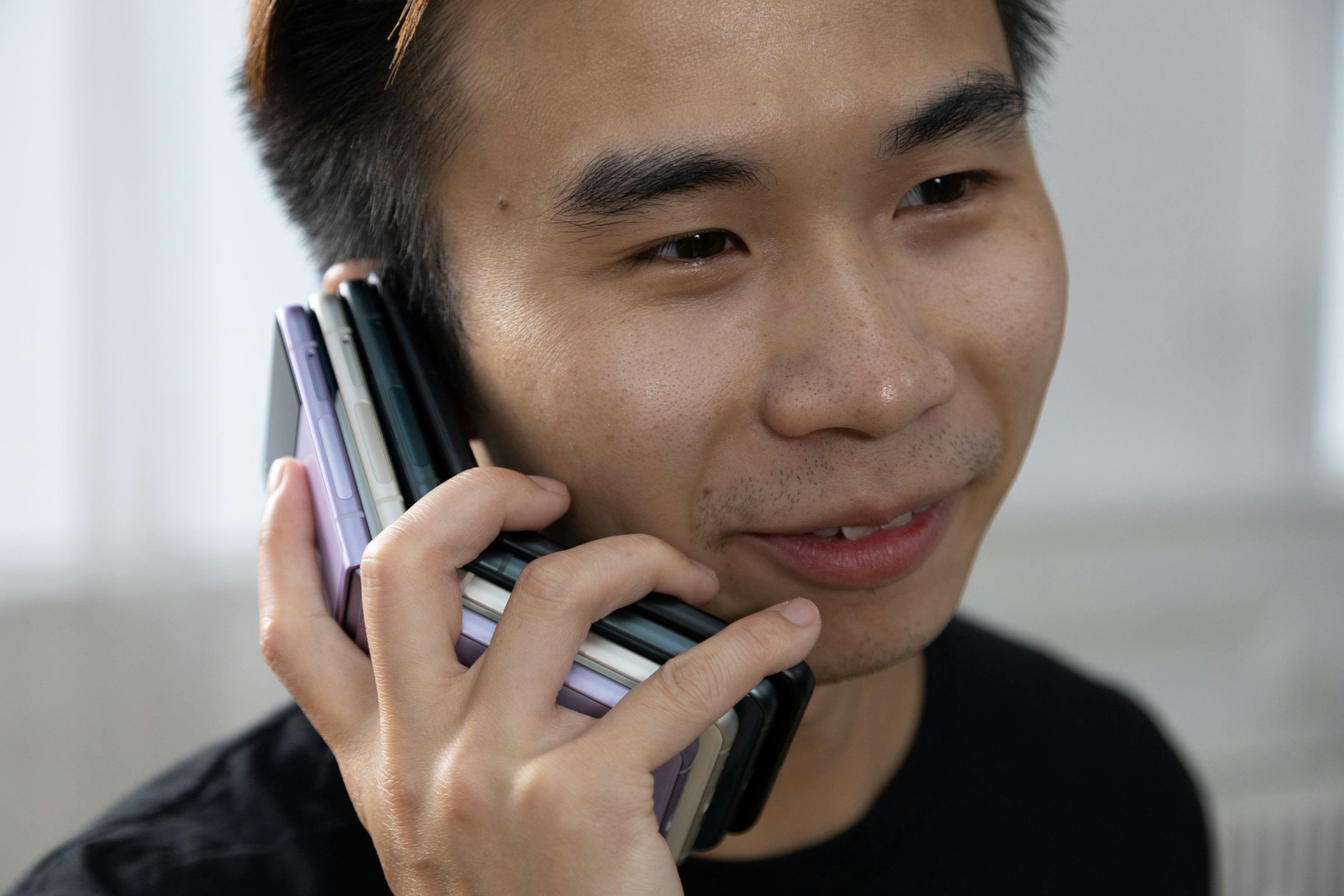Holding a stack of four Samsung Galaxy Z Flip 3 foldable Android smartphones
