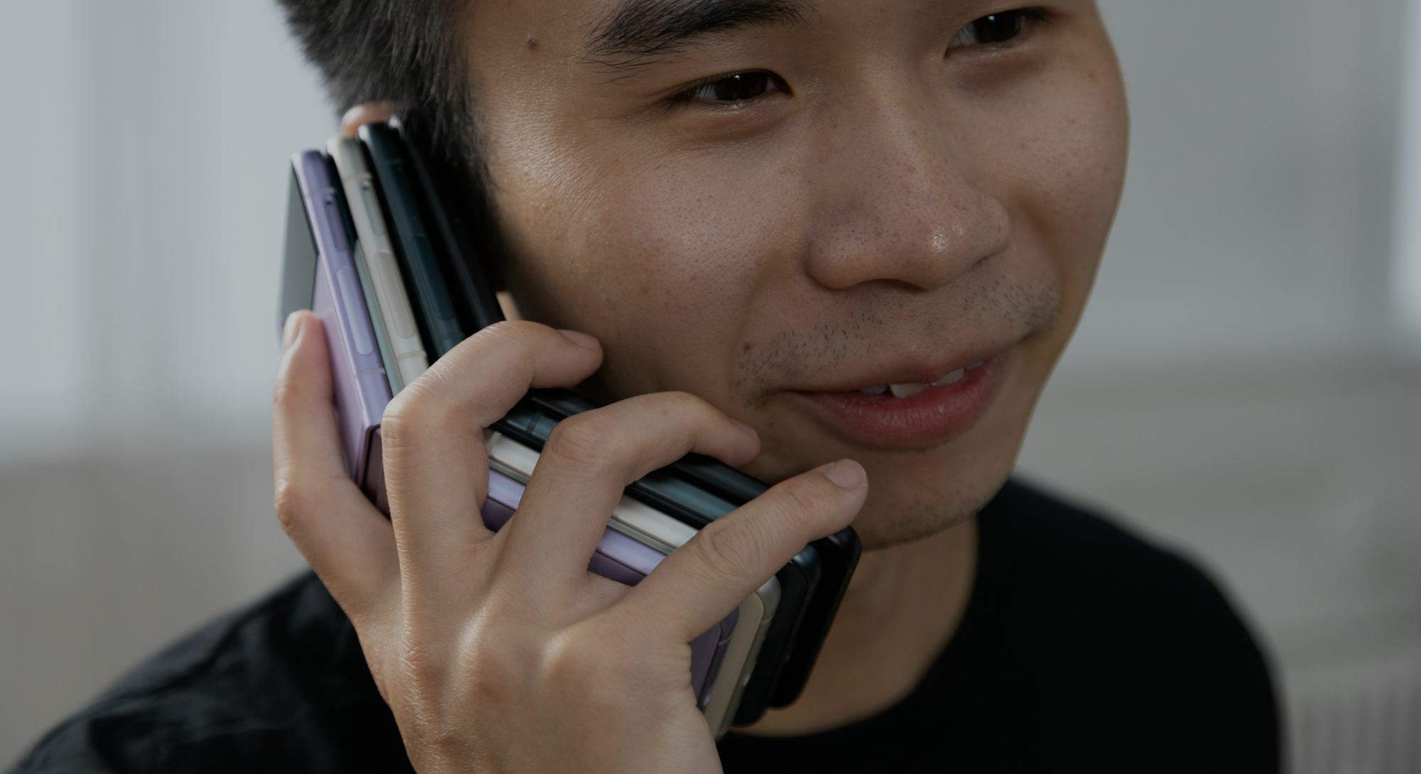 Holding a stack of four Samsung Galaxy Z Flip 3 foldable Android smartphones