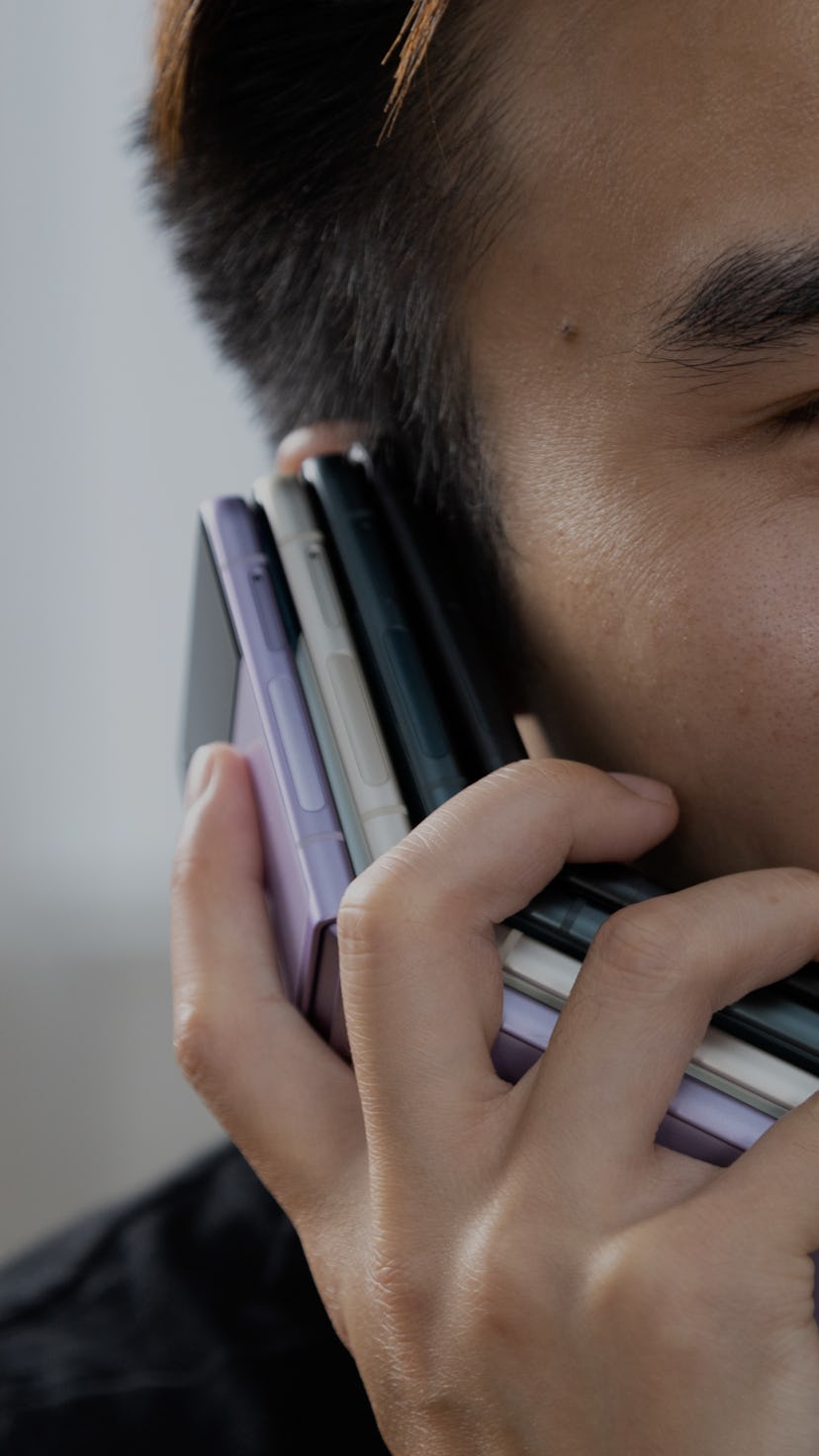 Holding a stack of four Samsung Galaxy Z Flip 3 foldable Android smartphones