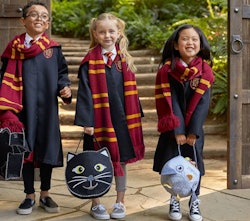 Three kids standing together, wearing "Harry Potter" costumes and holding Halloween buckets