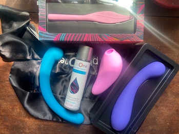 Pink, blue, and purple vibrators are pictured on a wooden table 