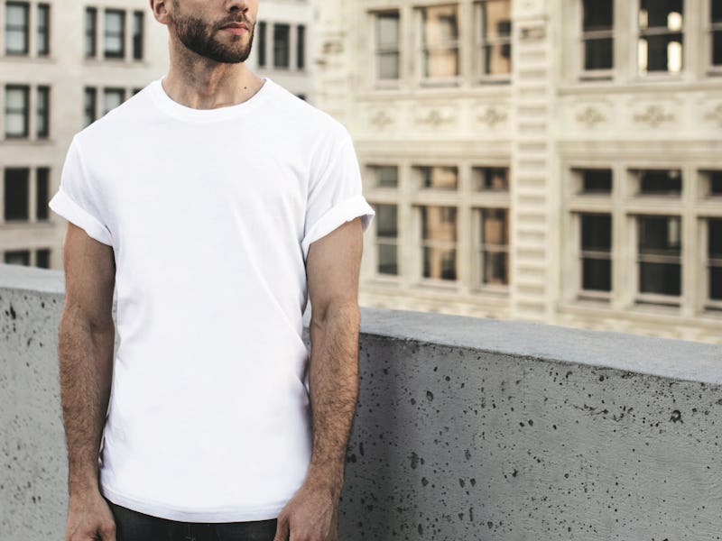 A man with a stubble, wearing a plain white t-shirt