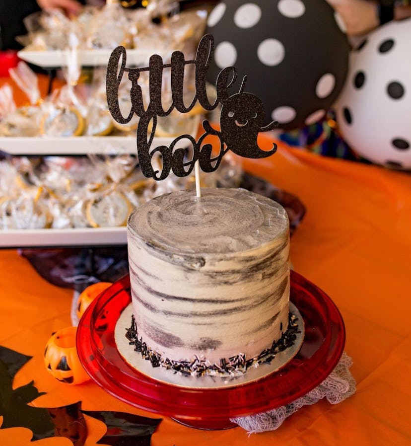 Chocolate cake with white icing and cake topper that says "little boo"