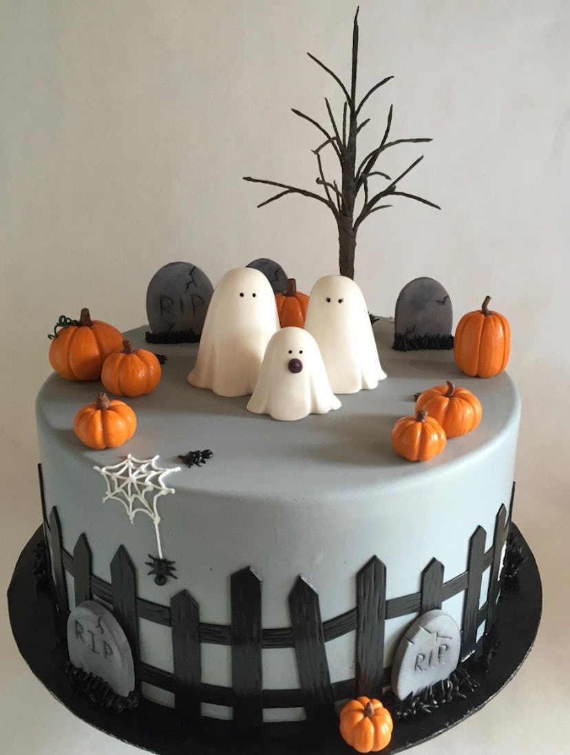 Single layer cake, grey with headstones and black picket fence all around, topped with ghosts and pu...