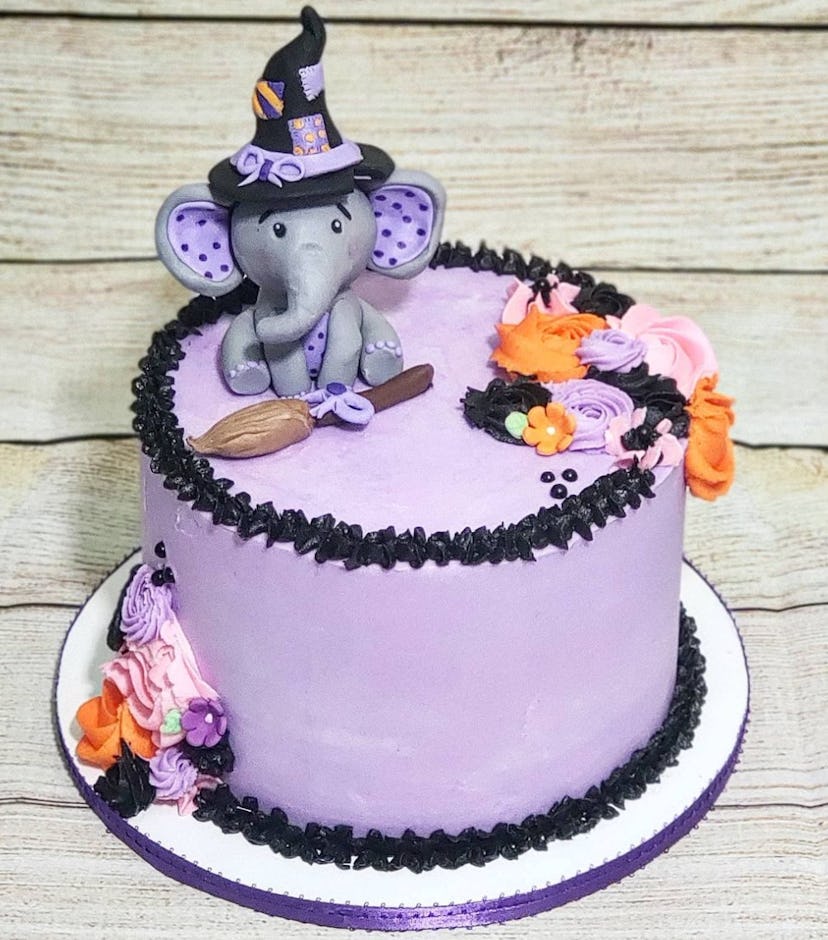 Purple and black cake with baby elephant wearing a witch's hat