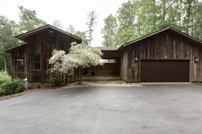 A modern cabin in Bakersville, North Carolina above the North Toe River with a garage, a paved drive...