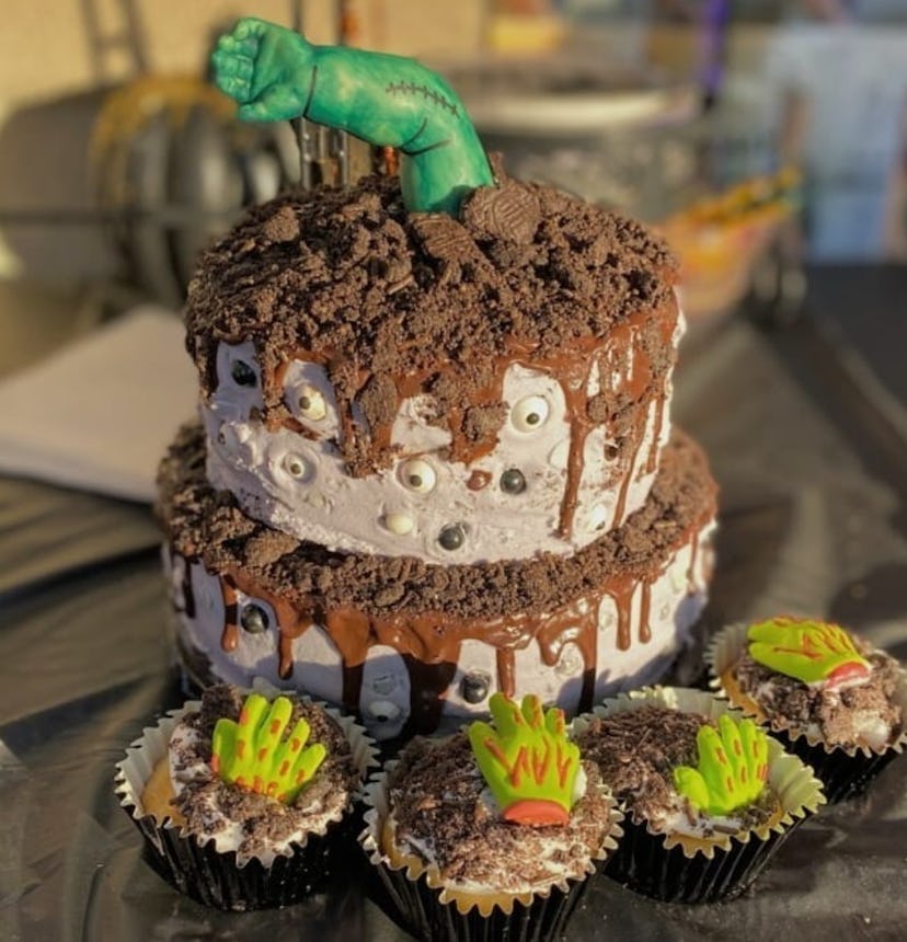 Two layer cake with baby arm decorated to look like a zombie/monster coming out like it's coming out...