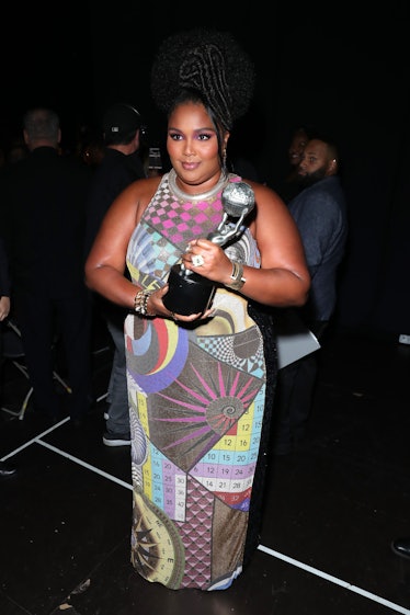 Lizzo in a mutlicolored dress with a trophy. 