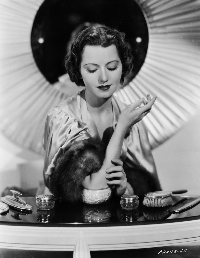 A black and white photo of a woman applying lotion