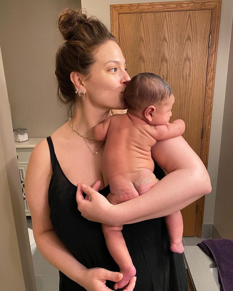 Mom, supermodel Ashley Graham holding her son Isaac while kissing his head.