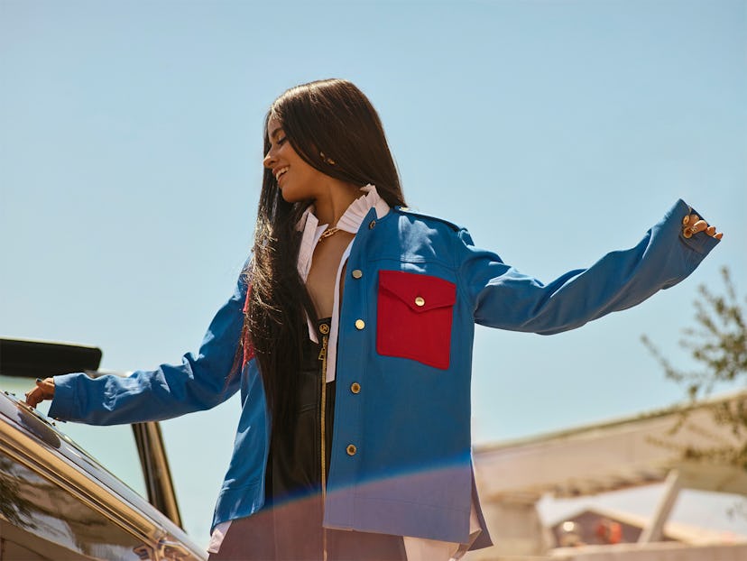 Bustle cover star Camila Cabello stands outside wearing a blue and red jacket by Louis Vuitton.
