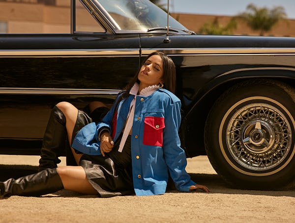 Bustle cover star Camila Cabello poses against a vintage car wearing a blue and red Louis Vuitton ja...