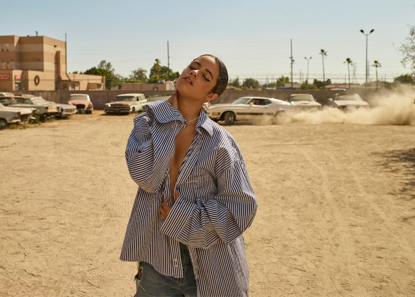 Bustle cover star Camila Cabello wears Balenciaga jeans and a blue and white striped button-up shirt...