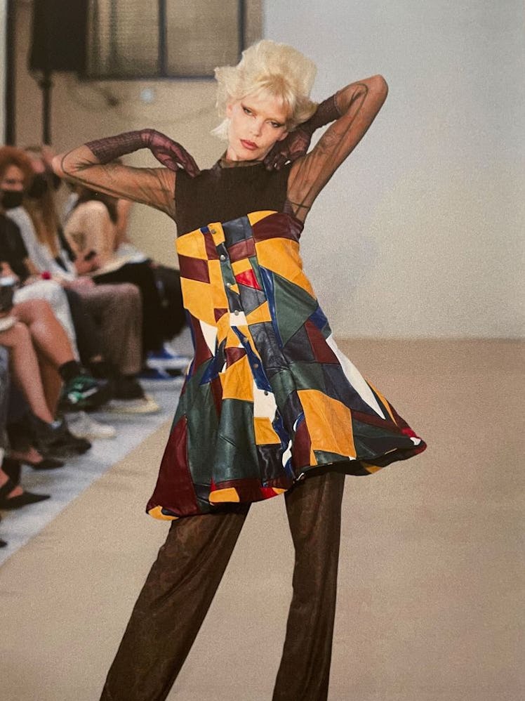 A model in a multipatterned and multicolored dress and brown pants by Louise Lyngh Bjerregaard