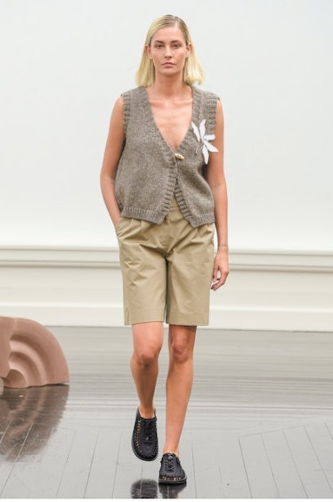 A model walking in a grey knit vest and beige shorts at Skall Studio's show for Copenhagen Fashion W...