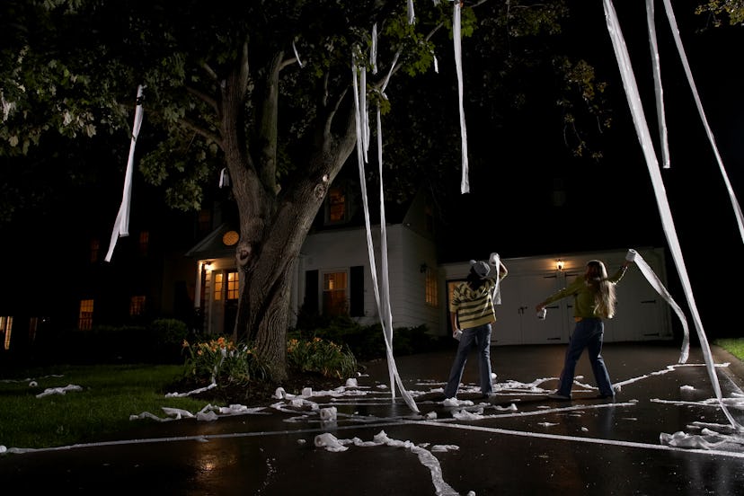 Two kids throwing toilet paper over a tree, TPing a house