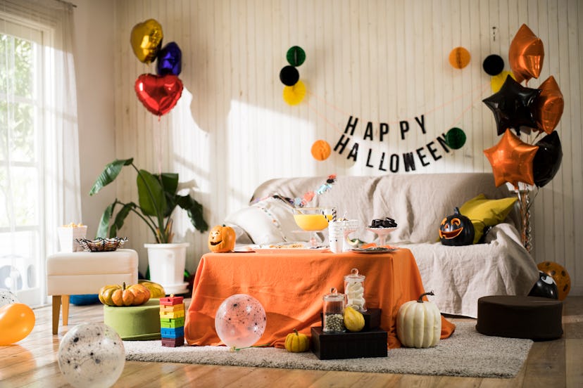 A couch with Halloween decor all around it, and a coffee table with orange drape sitting in front. 