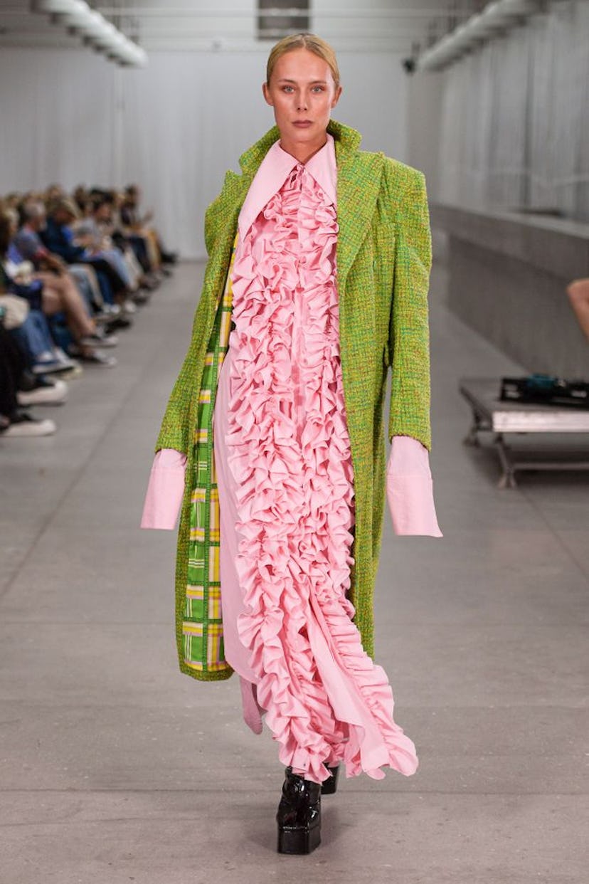 A model walking in a pink dress and green coat at the Copenhagen Fashion Week