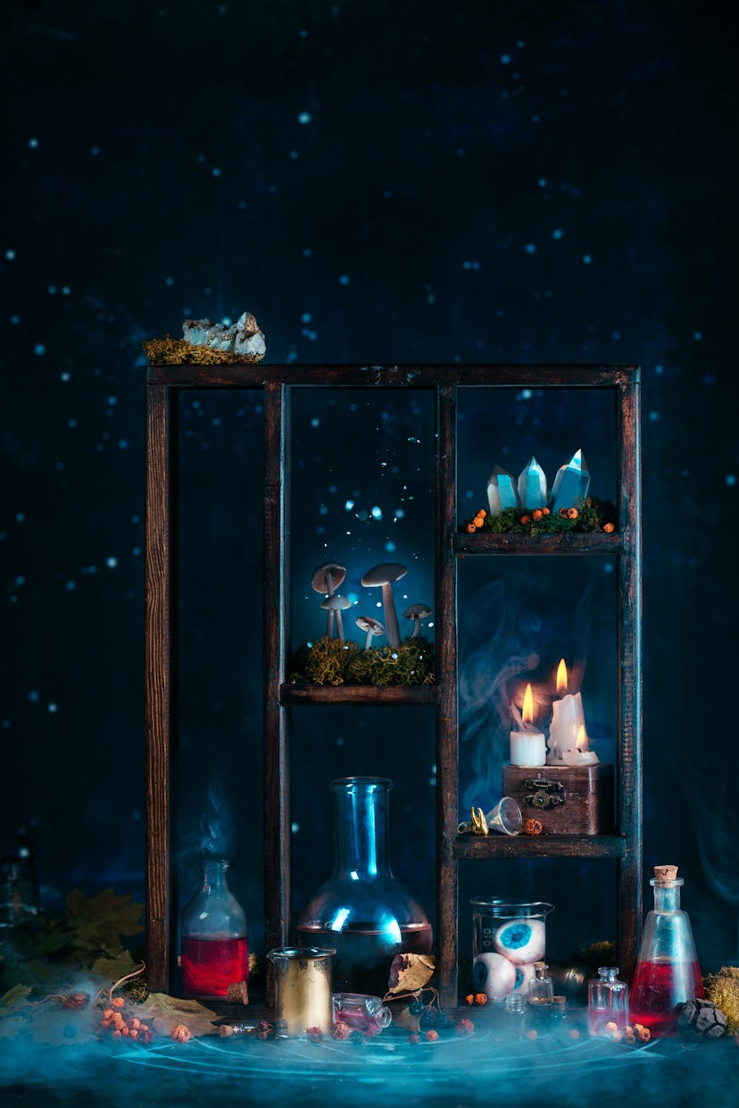 Shelving with beakers filled with colorful liquids, lit candles, and spooky Halloween decor