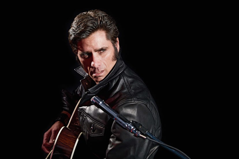 John Stamos as Elvis from the ‘68 Comeback Special in a black leather jacket, with a guitar