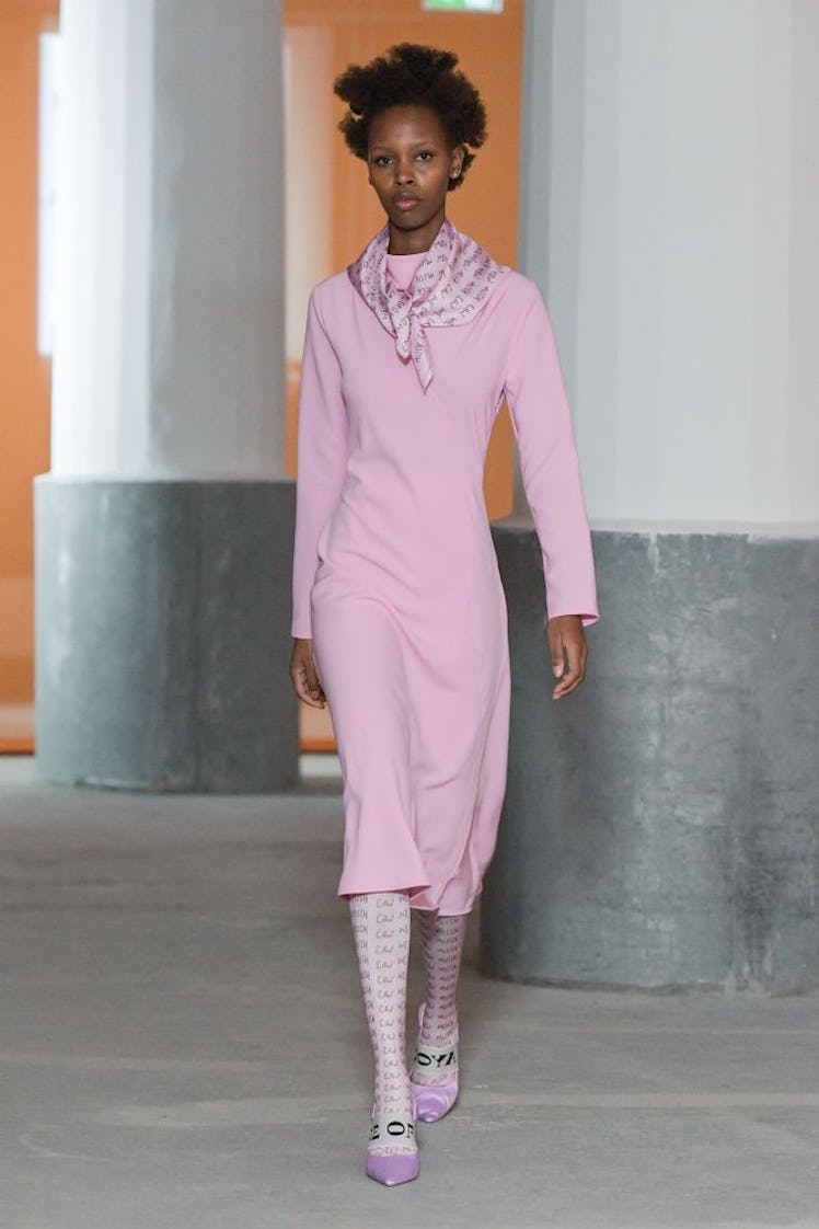 A model in a pink dress and matching silk scarf by Stine Goya