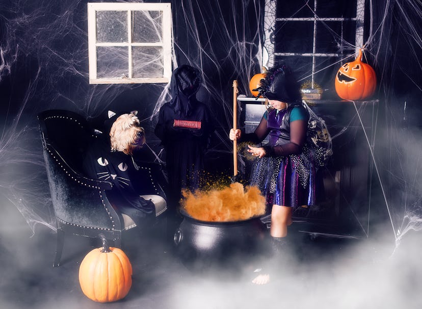 Little girl dressed up as a witch, stirring a pretend cauldron in haunted house 