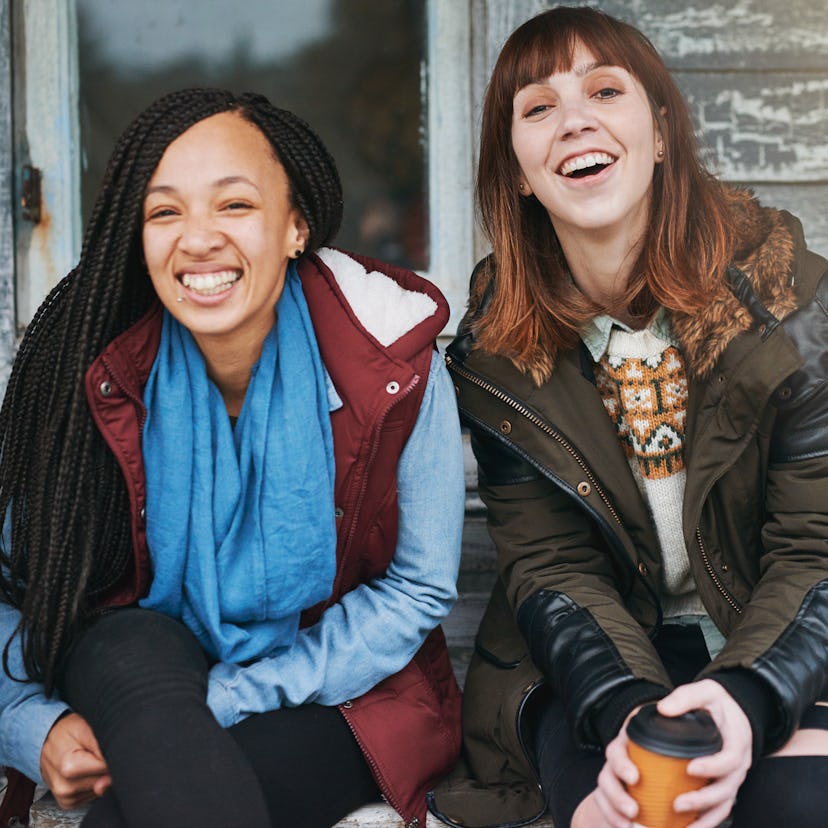 2 young woman laughing at a log cabin before posting a pic with a log cabin pun for Instagram captio...