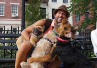 Ryan Fischer smiling and sitting on a bench with a bunch of happy dogs.