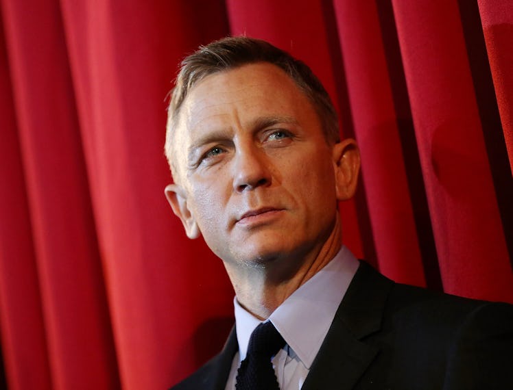 Daniel Craig wearing a black suit while posing for a photo.