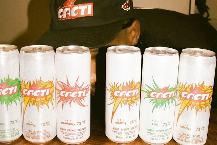 Travis Scott posing behind rows of Cacti spiked seltzer